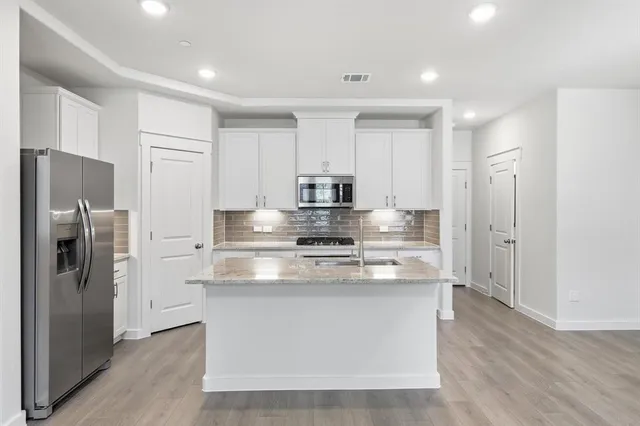 a kitchen with stainless steel appliances granite countertop a refrigerator and a stove top oven