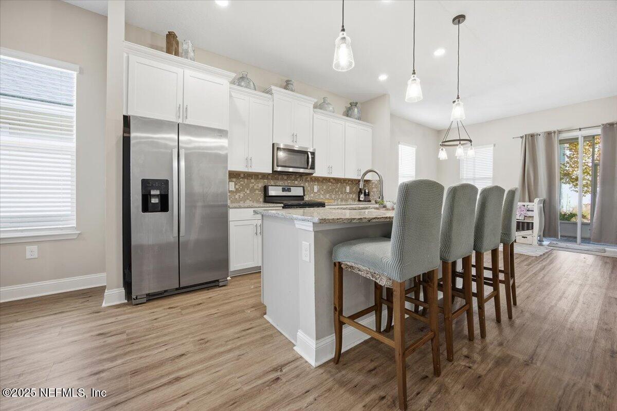 230 Julep Street Yulee, FL 32097 - Photo 5 of 24 a kitchen with stainless steel appliances granite countertop a refrigerator a stove a sink dishwasher a dining table and chairs with wooden floor