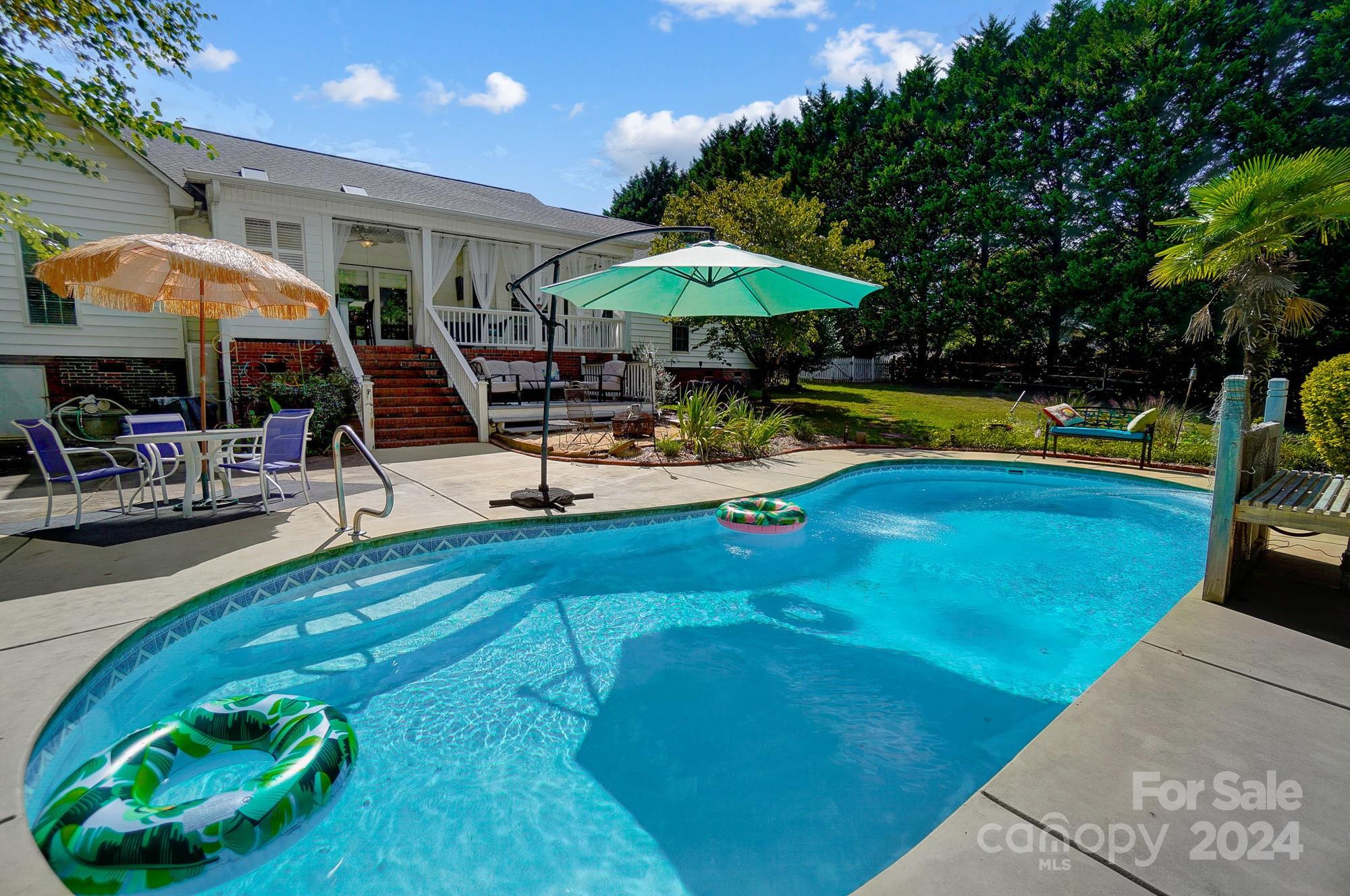8387 Fairfield Forest Road Denver, NC 28037 - Photo 35 of 38 a view of a swimming pool with a table and chairs under an umbrella