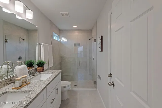 a bathroom with a granite countertop sink a toilet and shower