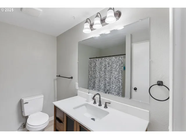 a bathroom with a sink vanity granite toilet and a mirror