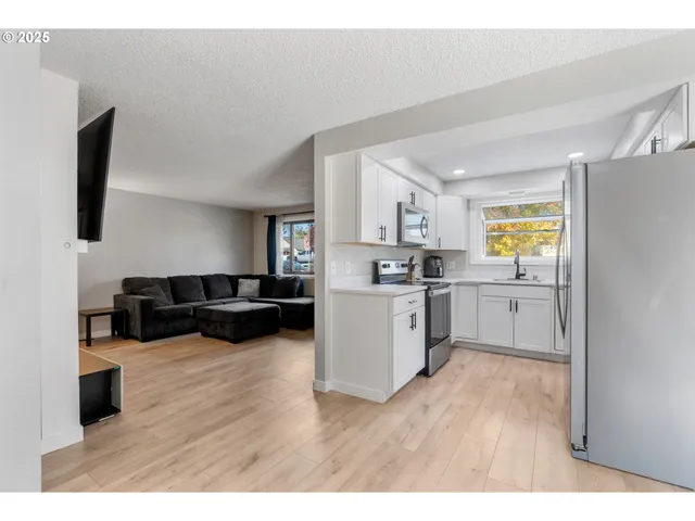 a kitchen with stainless steel appliances a refrigerator a sink a stove and white cabinets