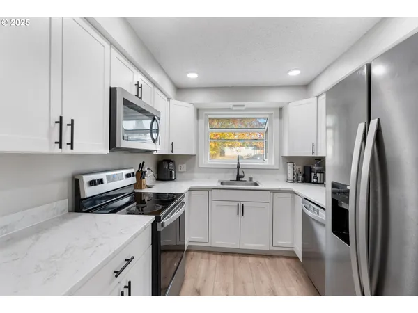 a kitchen with stainless steel appliances a sink stove refrigerator and cabinets