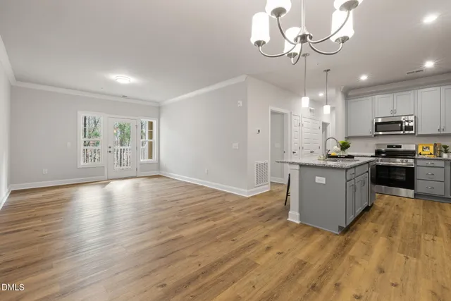 a view of kitchen with granite countertop stainless steel appliances cabinets a wooden floor and a fireplace