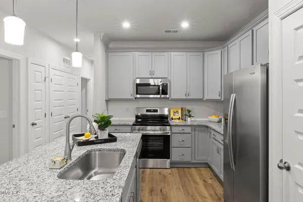 a kitchen with granite countertop a refrigerator a stove a sink a washer and dryer
