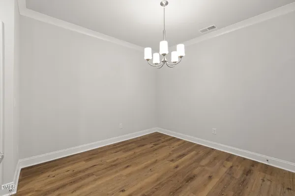 a view of empty room with wooden floor and chandelier