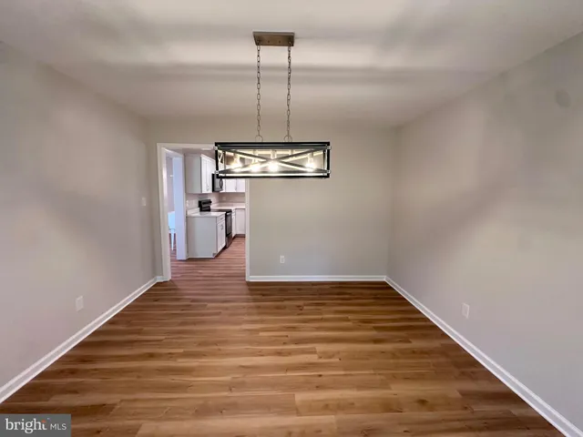 a view of an empty room with wooden floor and a ceiling fan
