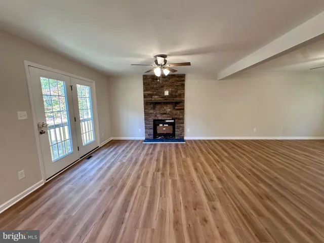 a view of kitchen and empty room with wooden floor