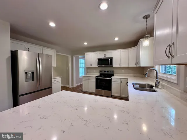 a large kitchen with granite countertop a large counter top stainless steel appliances and wooden floors