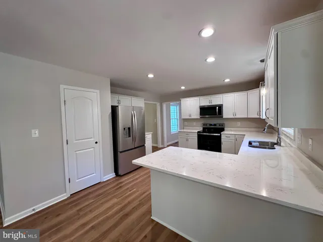 a large kitchen with a lot of counter space and wooden floor