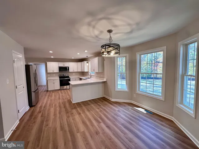 a large kitchen with cabinets wooden floor and stainless steel appliances