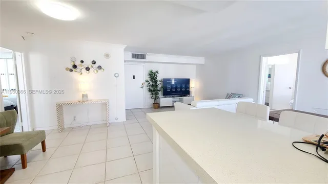 a large white kitchen with a sink and large mirror