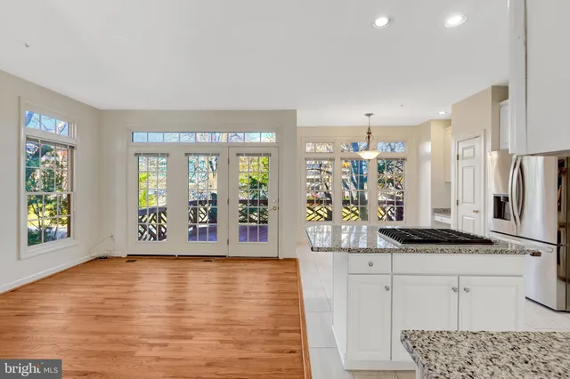 a large kitchen with stainless steel appliances kitchen island granite countertop a large window and a wooden floors
