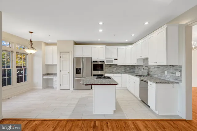 a kitchen with granite countertop white cabinets and stainless steel appliances