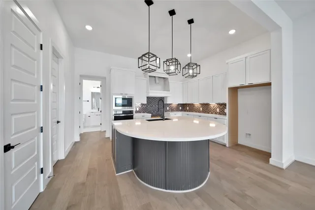 a large kitchen with stainless steel appliances a kitchen island a stove a refrigerator a dining table and chairs