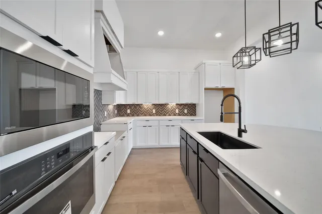 a kitchen with stainless steel appliances granite countertop a sink a stove and cabinets