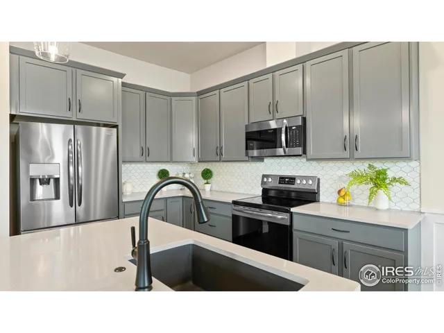 a kitchen with stainless steel appliances a sink a stove a microwave a refrigerator a counter space and cabinets
