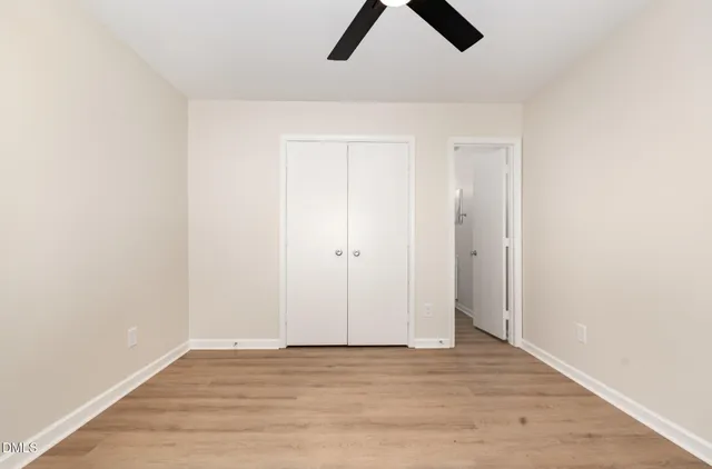 a view of an empty room with wooden floor and window