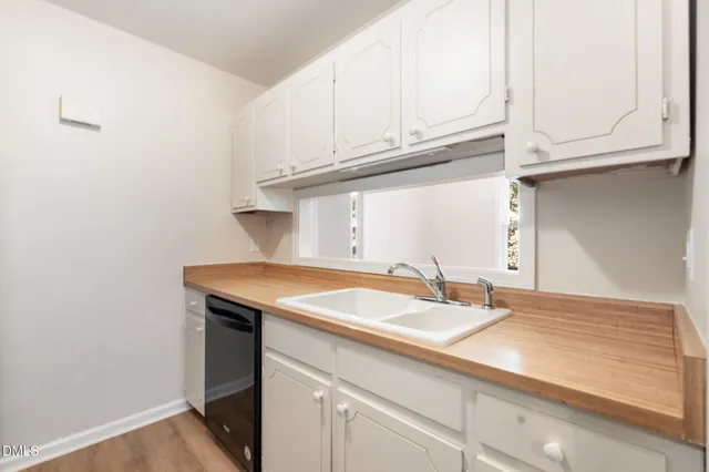an empty room with wooden floor fireplace and windows