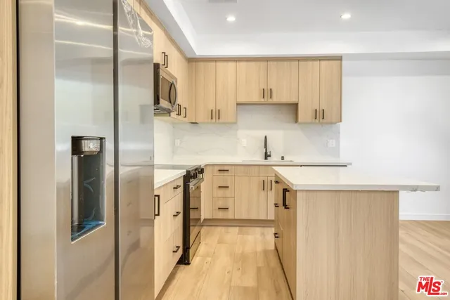 a view of kitchen with kitchen island wooden floor center island and stainless steel appliances