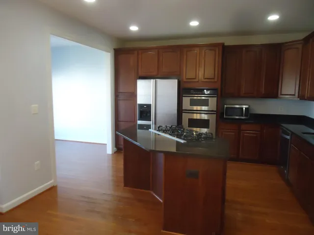 a kitchen with kitchen island granite countertop wooden cabinets a sink and stainless steel appliances
