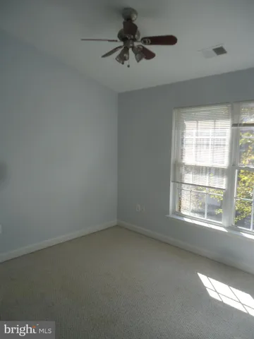 an empty room with a window and a ceiling fan