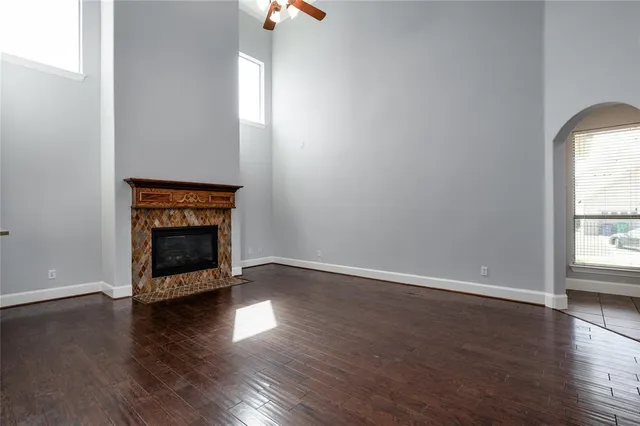 an empty room with wooden floor fire place and a window