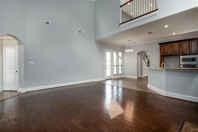 an empty room with wooden floor and a kitchen
