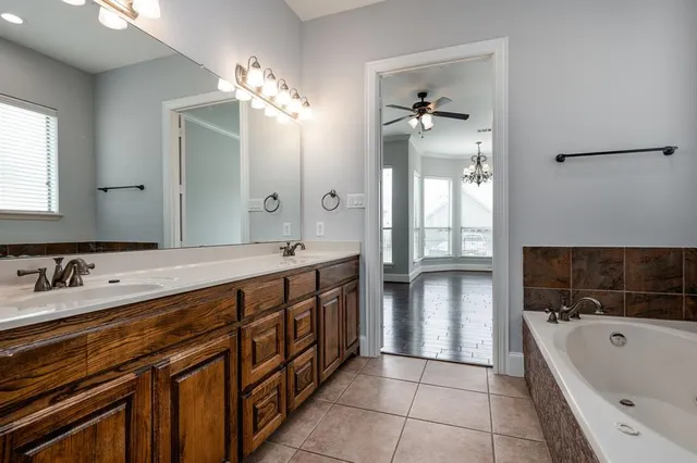 a spacious bathroom with a double vanity sink a large mirror and a bathtub