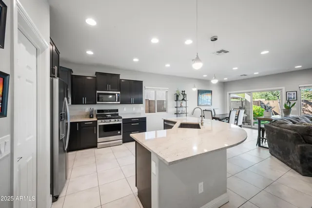 a large kitchen with kitchen island a sink a counter top stainless steel appliances and cabinets