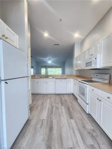 a kitchen with granite countertop white cabinets and white appliances