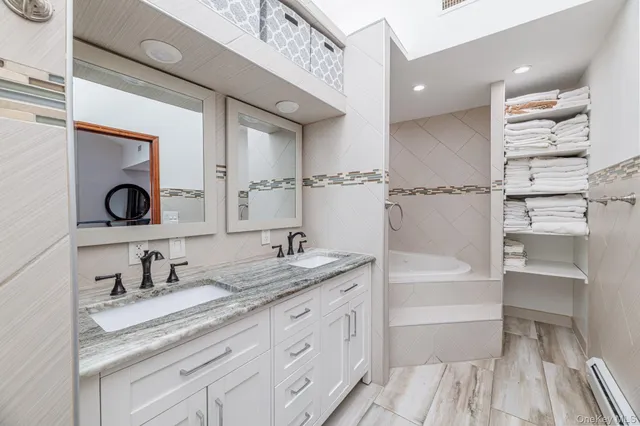 a bathroom with a granite countertop sink a mirror a vanity and a bathtub