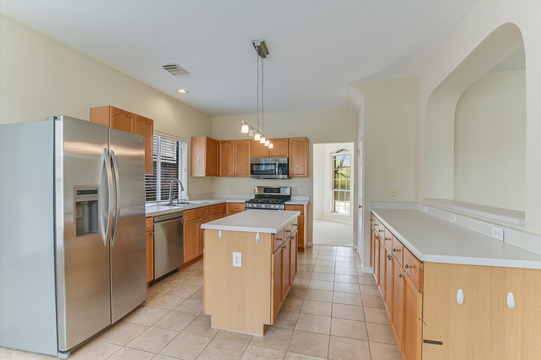 2218 Equestrian Trail Austin, TX 78727 - Photo 12 of 39 Kitchen with stainless steel appliances, a center island, light countertops, light tile patterned flooring, and decorative light fixtures