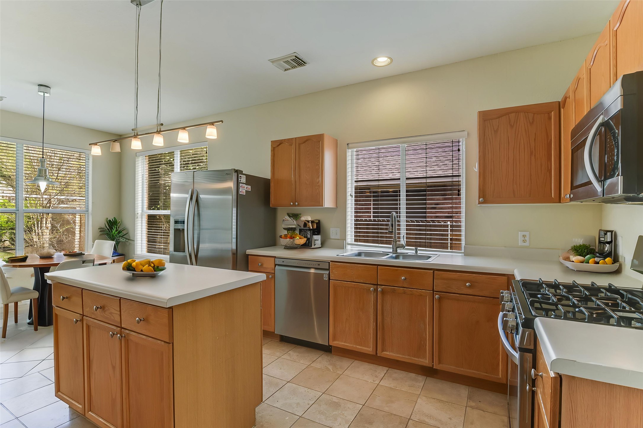 2218 Equestrian Trail Austin, TX 78727 - Photo 13 of 39 Virtually Staged: Kitchen featuring stainless steel appliances, light countertops, a kitchen island, light tile patterned floors, and pendant lighting