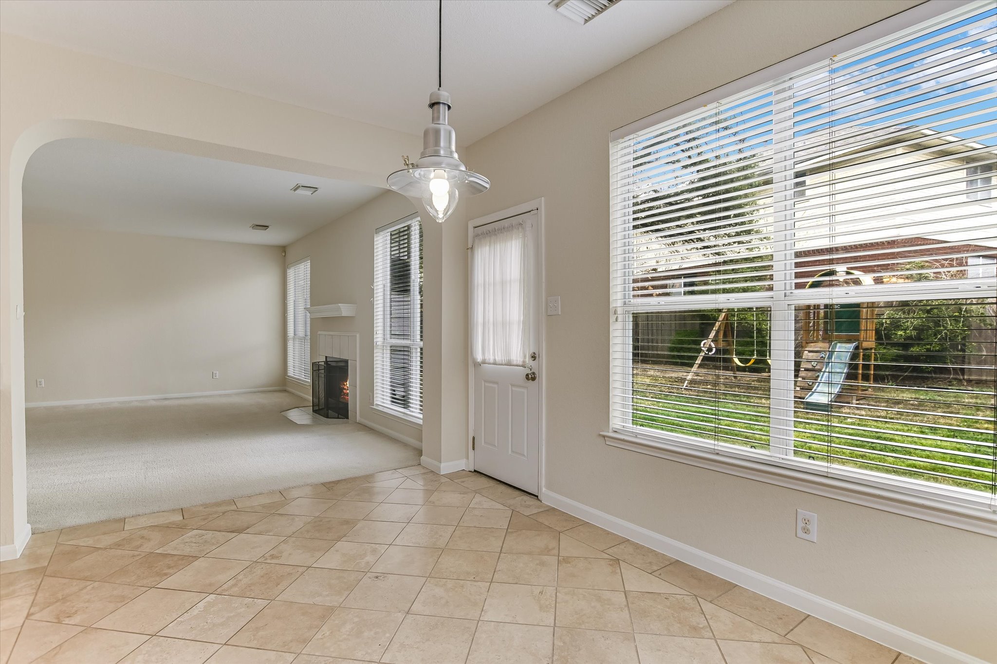 2218 Equestrian Trail Austin, TX 78727 - Photo 19 of 39 Foyer with light tile patterned floors, a fireplace with flush hearth, arched walkways, and light carpet