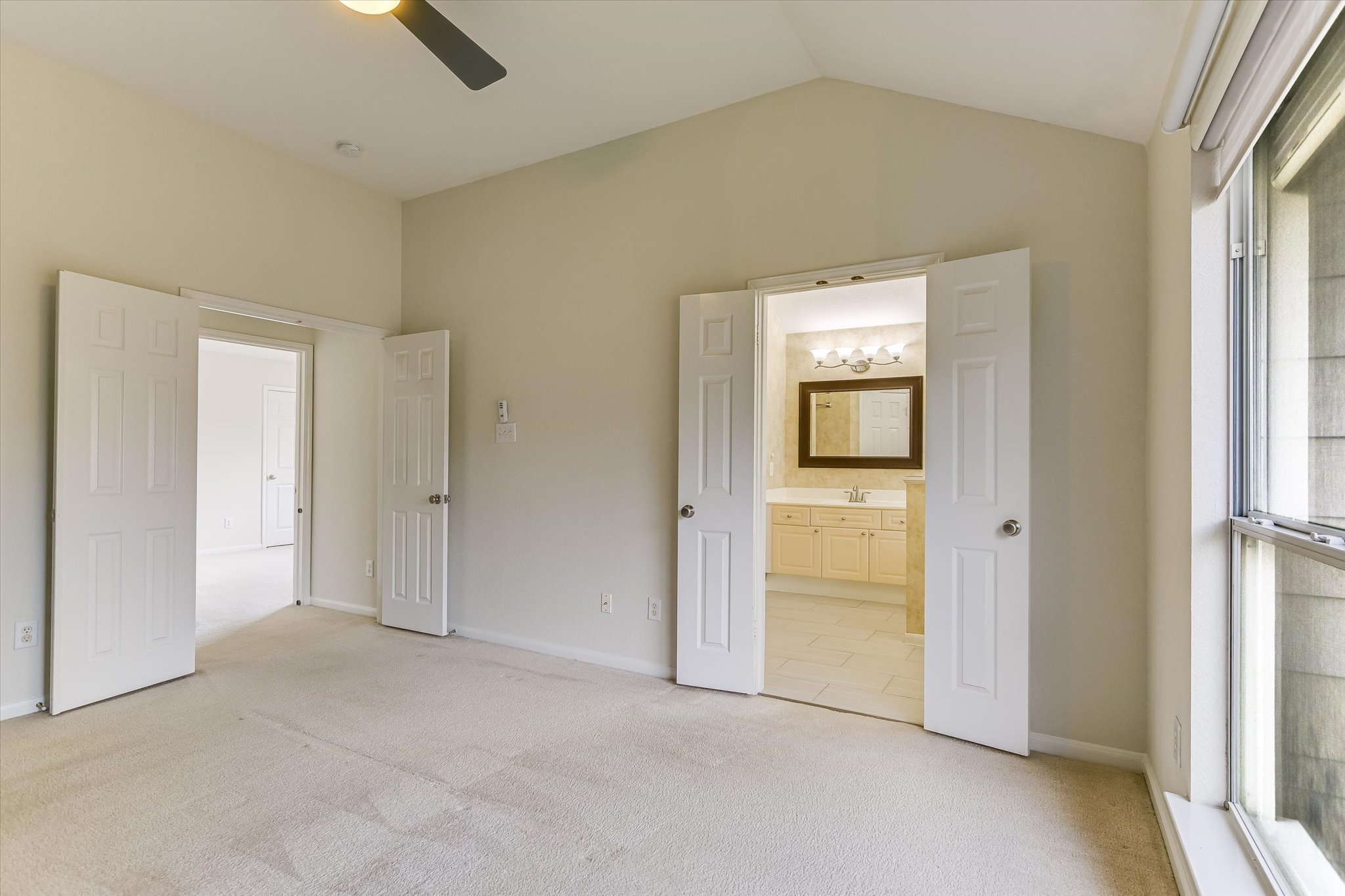 2218 Equestrian Trail Austin, TX 78727 - Photo 27 of 39 Unfurnished bedroom with light carpet, connected bathroom, and ceiling fan