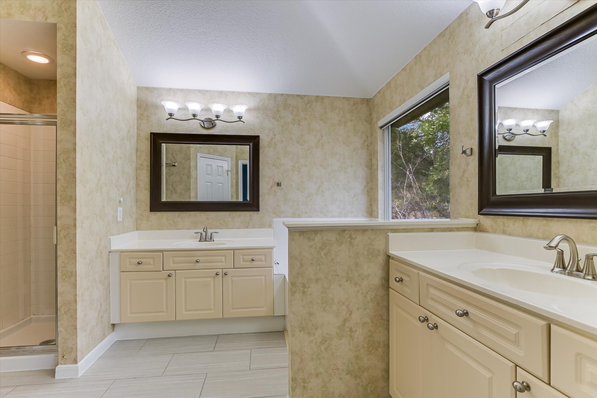 2218 Equestrian Trail Austin, TX 78727 - Photo 29 of 39 Full bath featuring a shower stall, two vanities, a textured ceiling, and light tile patterned floors