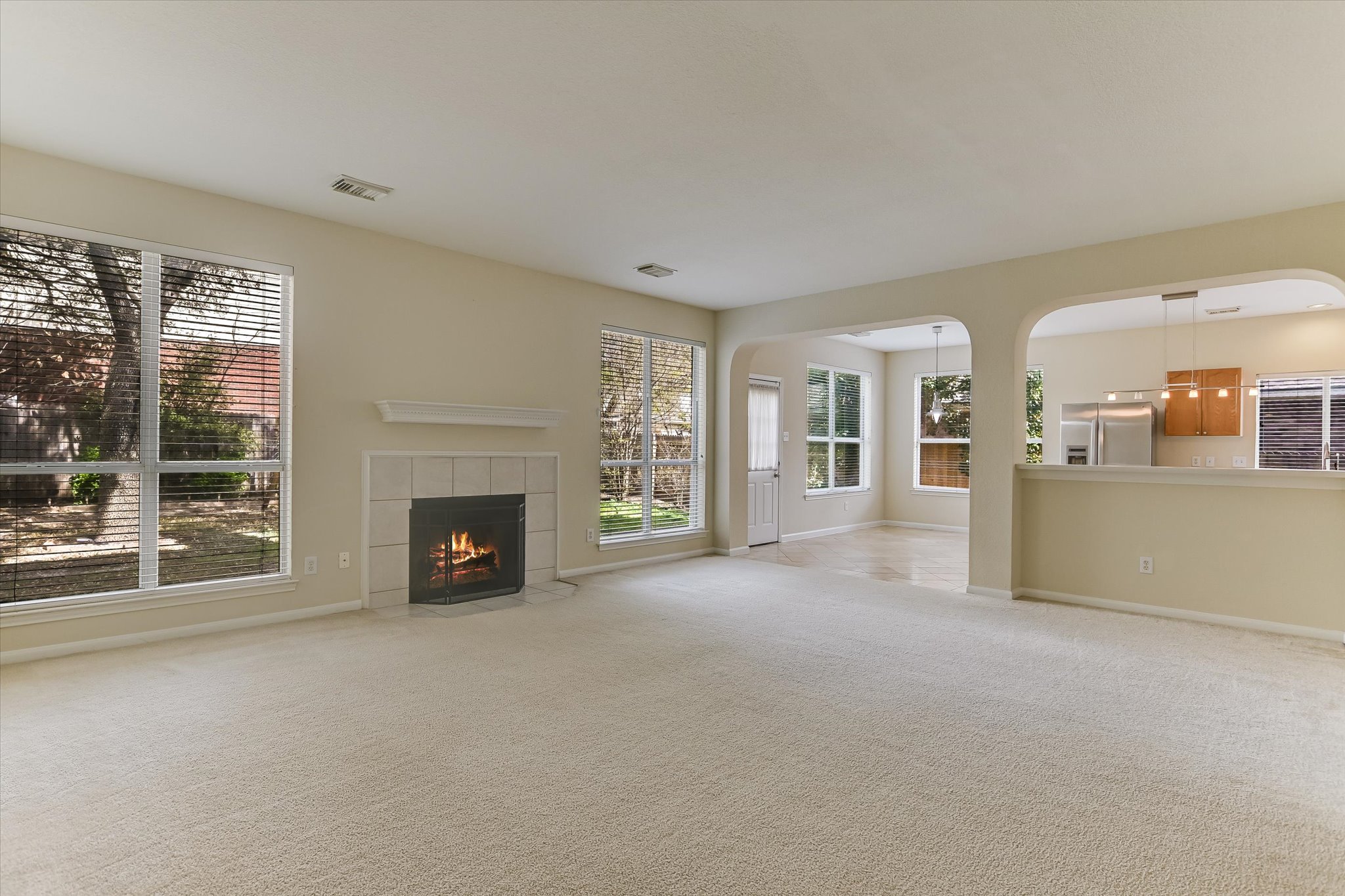 2218 Equestrian Trail Austin, TX 78727 - Photo 5 of 39 Unfurnished living room featuring light carpet, arched walkways, and a tiled fireplace