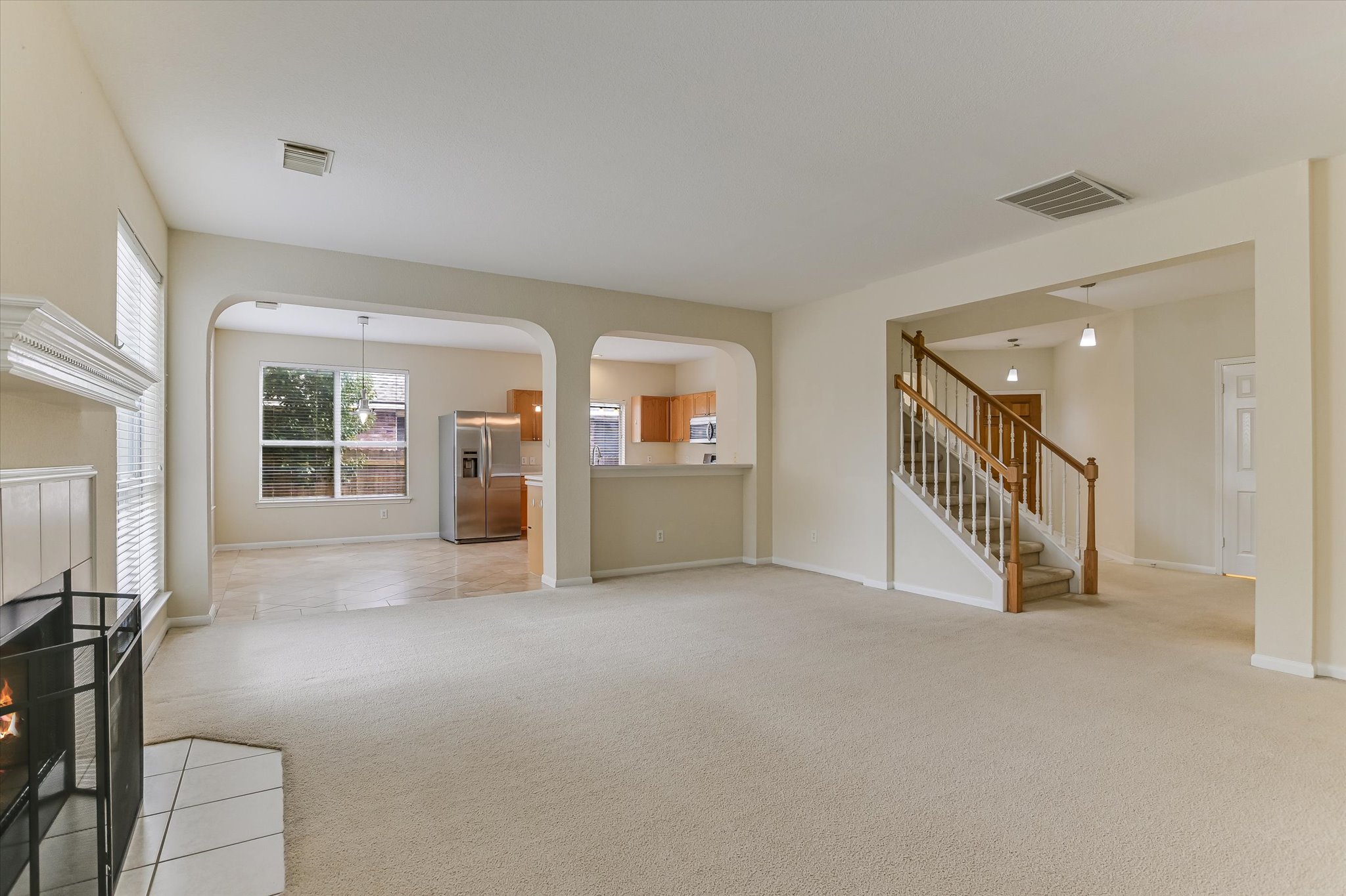 2218 Equestrian Trail Austin, TX 78727 - Photo 7 of 39 Unfurnished living room featuring a tile fireplace, light carpet, and arched walkways