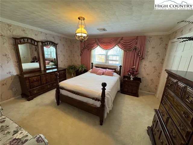 a spacious bedroom with a bed mirror and window