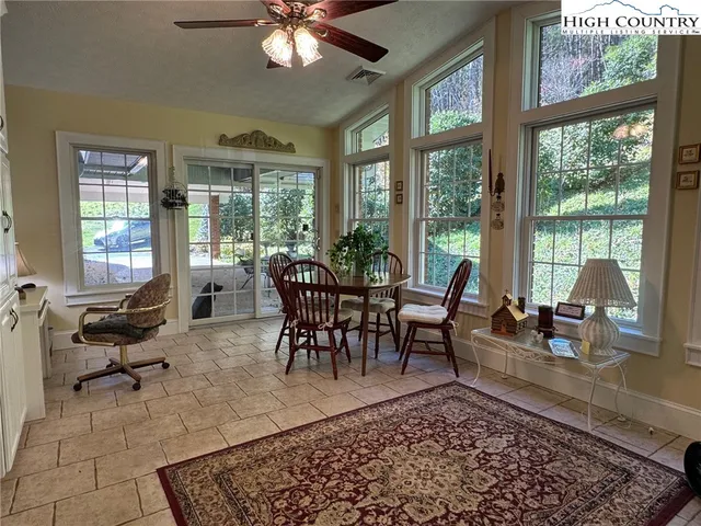 a living room with furniture a rug a lamp large windows and a table