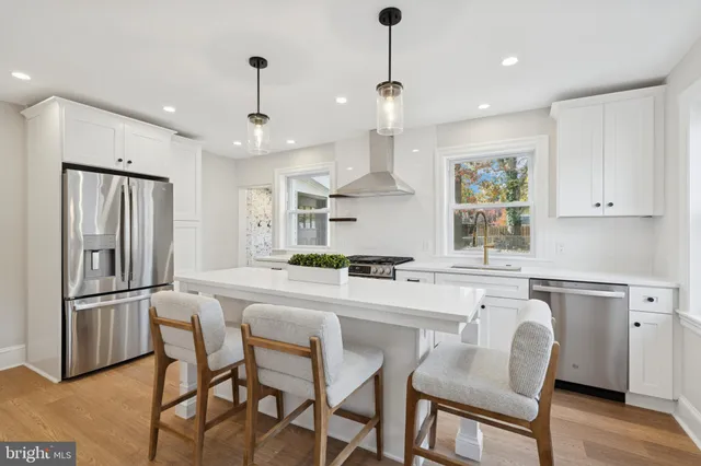 a kitchen with stainless steel appliances granite countertop a dining table chairs refrigerator and microwave