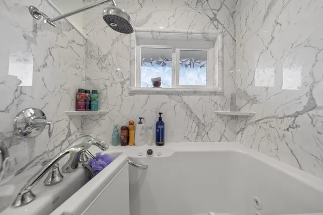 a bathroom with a tub sink vanity and mirror
