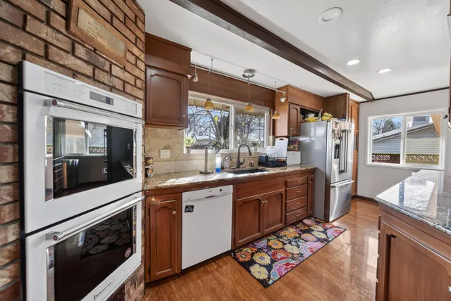 a large kitchen with stainless steel appliances granite countertop a sink and wooden cabinets