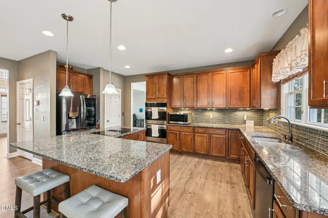 a kitchen with stainless steel appliances granite countertop a sink stove and refrigerator