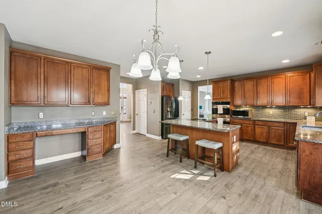 a large kitchen with granite countertop lots of counter space dining table and stainless steel appliances