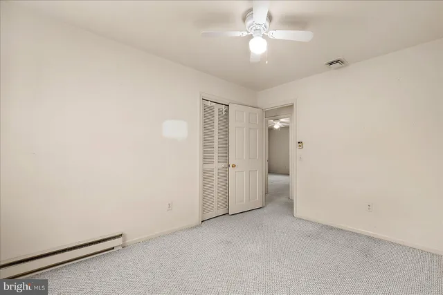 an empty room with chandelier fan and windows