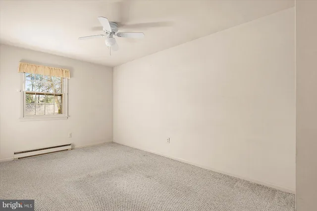 an empty room with a window and ceiling fan
