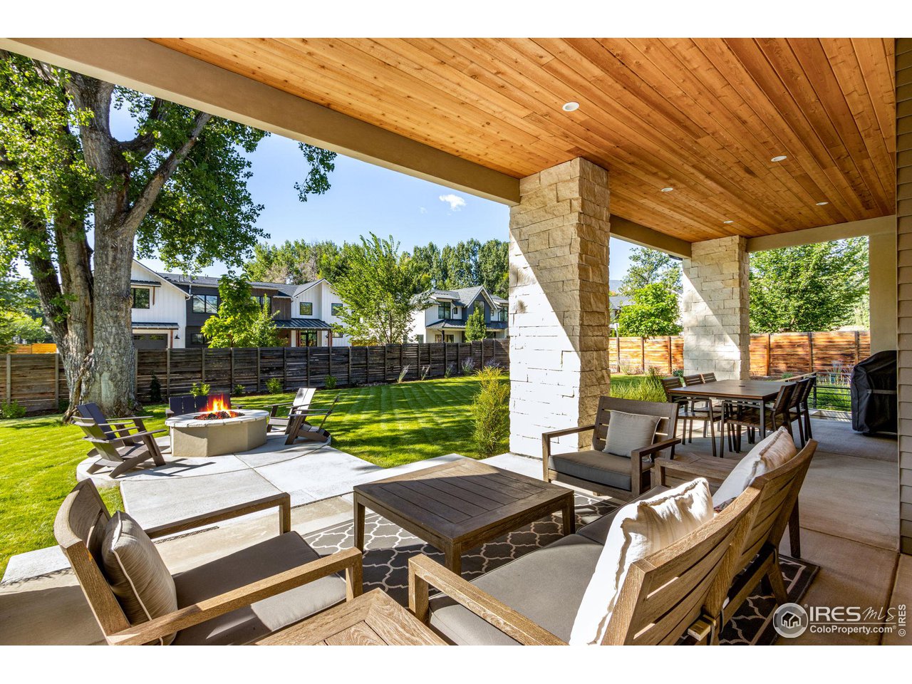 a view of a patio with couches potted plants and a large tree