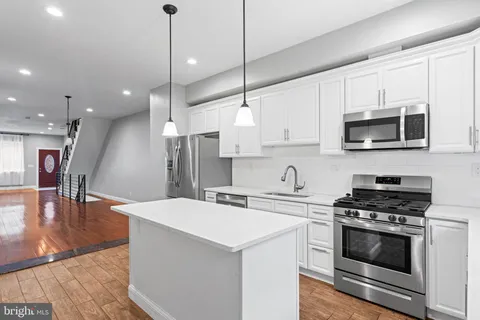 a kitchen with stainless steel appliances kitchen island a white cabinets and stove top oven